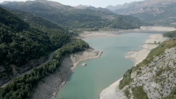 Flygfoto framåt skott över den sjunkande vattennivån i sjön Ayous under höstsäsongen med grön skog på båda sidor i Pyrenéerna i Frankrike. — Stockvideo