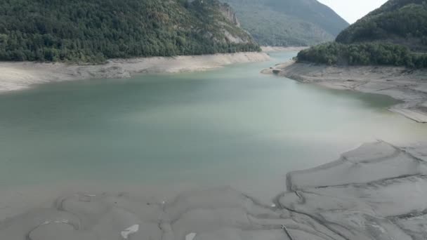 Drone shot of receded water levels of Lake Ayous and beautiful lush green pine forest by its banks on a cloudy day in the Pyrenees in France. Effets du réchauffement climatique. — Video