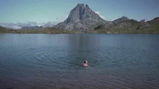 Vedere a unei tinere doamne care iese din lac Ayous după ce a făcut baie în lacul albastru curat într-o dimineață însorită strălucitoare în Pirineii din Franța. — Videoclip de stoc