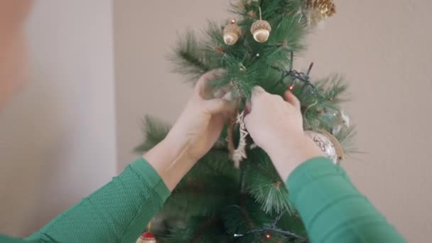 Παλιά λευκή γυναίκα κρεμούσε στολίδια στο χριστουγεννιάτικο δέντρο. Επιλογή εστίασης — Αρχείο Βίντεο