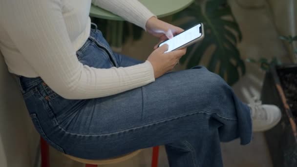 Donna seduta su una sedia e chattare con l'amico digitando con entrambe le mani sul suo telefono — Video Stock