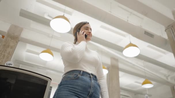 Blank vertrouwen Jonge Zakelijke vrouw in witte trui is praten over de telefoon in Modern Office - low angle view — Stockvideo