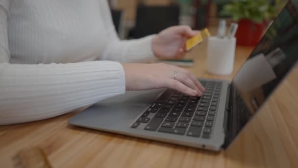 Női kezek kezében egy hitelkártya és gépelés kitöltési számot online fizetés a laptopon — Stock videók
