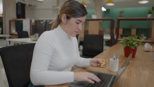 Nő online vásárlás hitelkártyával gépelési kártyák száma laptop az irodában — Stock videók