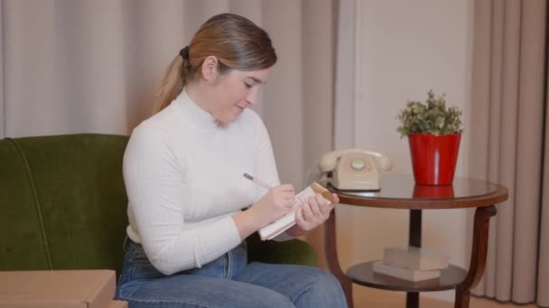 Affärskvinna antecknar i en anteckningsbok hemma. Kaukasiska kvinnliga entreprenör skriva schema i en dagbok — Stockvideo