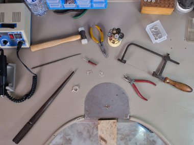 Atölyesindeki kuyumcunun tezgahında çeşitli aletler var.