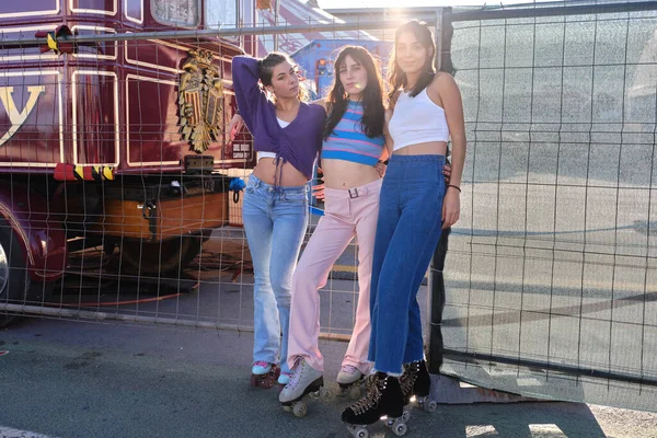 Drie vrouwen met een skate poserend naast een hek van een circus op een zonnige dag — Stockfoto