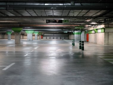 Boş araba parkı, yerde sütunlar ve tabelalar var.