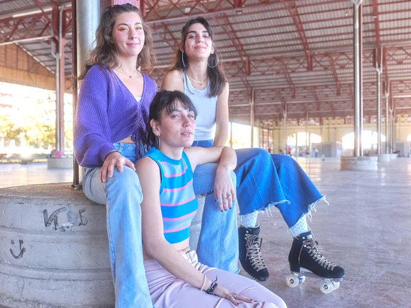 Három tini barátok pózol, miközben ül egy városi területen visel osztálykorcsolyát — Stock Fotó
