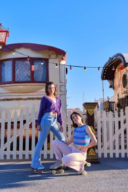 Sirk gösterisinin yanında iki eski elbise ve patenle poz veren iki arkadaş.