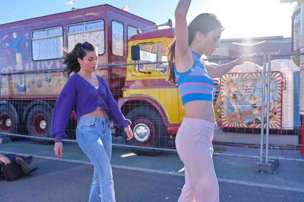Twee vrienden in vintage kleding schaatsen op een parkeerplaats naast een circus parade — Stockfoto