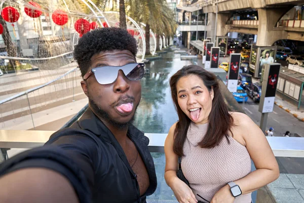 Divertido afican homem e asiático mulher grimacinf para a câmera ao tomar um selfie — Fotografia de Stock