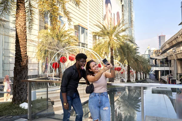 Multiethnic přátelé šklebí, zatímco se selfie mimo obchoďák v Asii — Stock fotografie