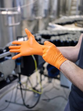 Bira fabrikasında lateks eldiven takan bir işçinin dikey fotoğrafı