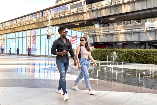 İki çok ırklı arkadaş alışveriş merkezinin açık alanlarında yürüyorlar. — Stok fotoğraf