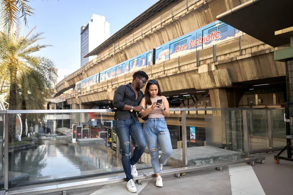 Two serious friends using the mobile in the entrance of a shopping mall — Stock Photo, Image