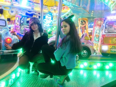 Arkadaşlar, geceleri adil bir çekim platformunda çömelirken poz verirler.