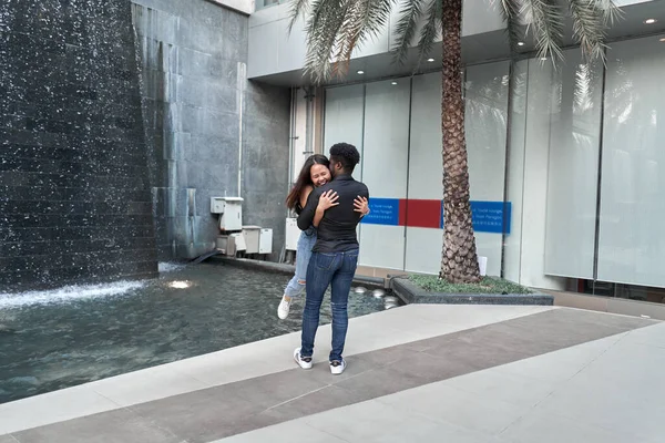 Multiethnic couple embracing in the middle of a shopping mall — Stock Photo, Image