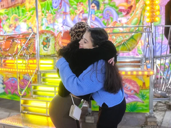 Två vänner kramar varandra på en nattmarknad — Stockfoto