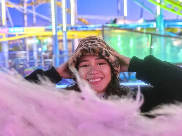 Mulher sorridente na frente de uma bola de algodão doce em uma feira à noite — Fotografia de Stock