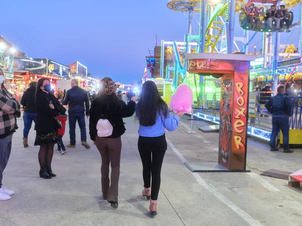 Назад двох жінок, які ходять під час їжі бавовняних цукерок на вечірньому ярмарку — стокове фото