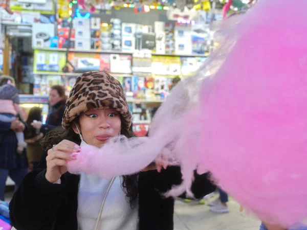 Mulher feliz comendo um algodão doce em um parque de diversões — Fotografia de Stock