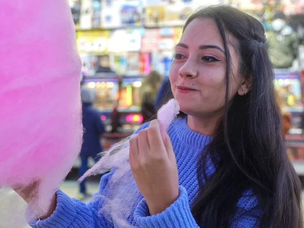 Menina olhando como se ela está desfrutando enquanto come um algodão doce à noite — Fotografia de Stock