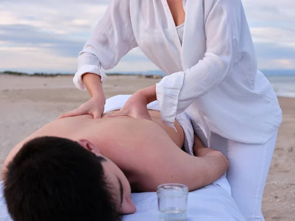 A young man receiving a chiromassage treatment by chiromassage therapist on a beach in Valencia. — Stock Photo, Image