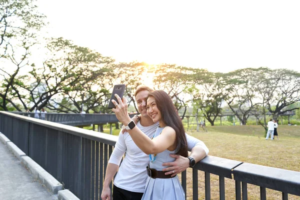 Paar macht bei Sonnenuntergang ein Selfie aus einem Park — Stockfoto