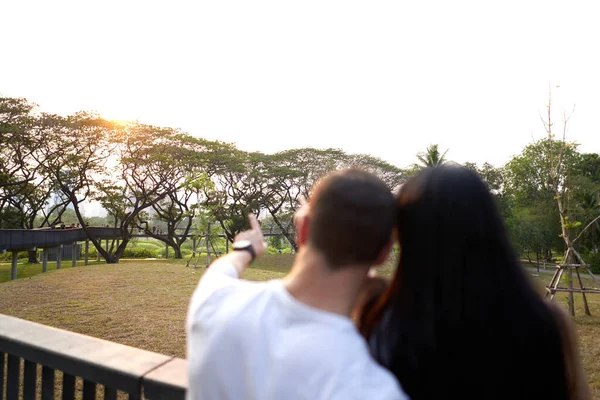 Paisagem de um parque enquanto um casal está olhando para ele durante o pôr do sol — Fotografia de Stock