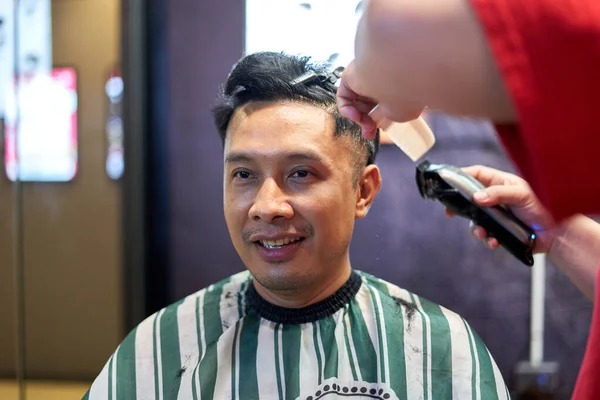 Portrait of a smiling asian man sitting on a barber shop — Zdjęcie stockowe