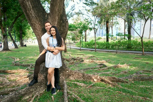 Photo with copy space of a newly married multicultural couple leaning on a tree — Foto Stock