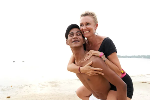 Couple in love piggyback riding on a tropical beach — ストック写真