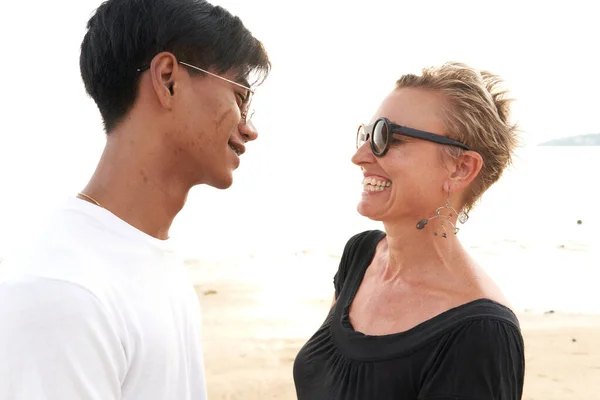 Multicultureel koppel glimlachend naar elkaar in een zandstrand — Stockfoto