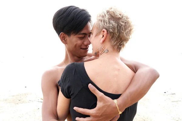 Couple gazing tenderly at each other while embracing on a beach at sunset — Fotografia de Stock