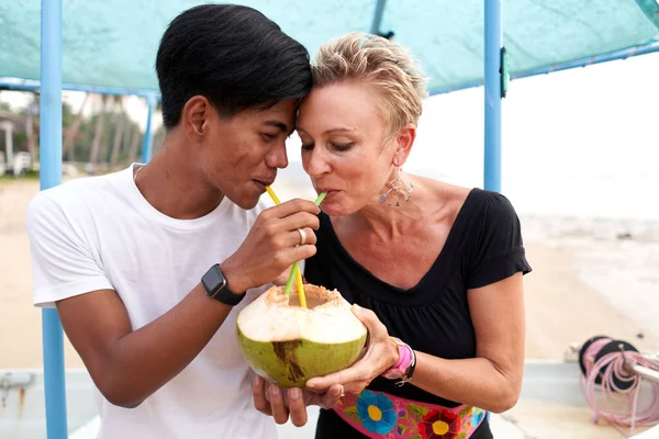 Multicultural couple sharing the juice of a fresh coconut — ストック写真