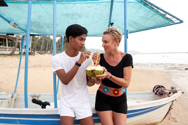 Multicultureel koppel drinken een natuurlijke kokosnoot in een strand — Stockfoto