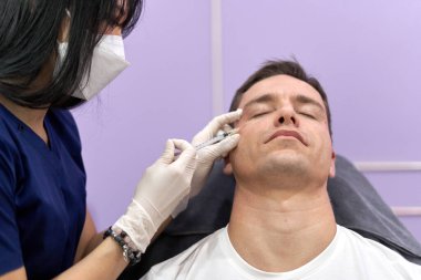 Yüz gençleştirme tedavisi için alnına botoks yapılan bir adam.