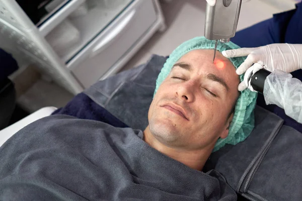 Relaxed man receiving a laser treatment to rejuvenate the skin — Fotografia de Stock