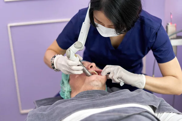 Doctor applying a facial rejuvenation treatment using laser to a man — Stock Photo, Image