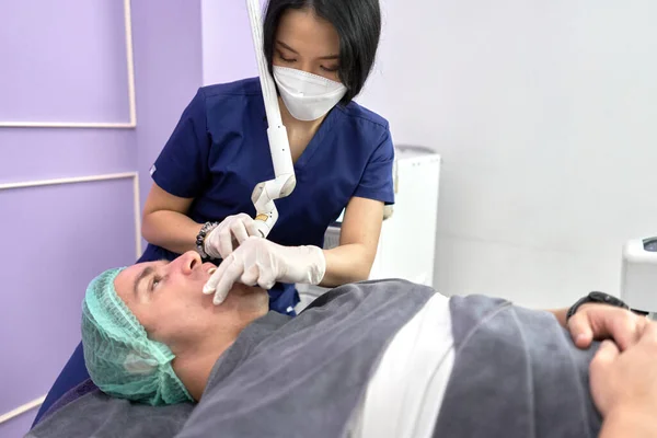Profile of a patient receiving a beauty treatment with laser in a clinic — Stock Photo, Image