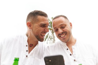 Eşcinsel çift cep telefonunu açık havada kullanırken birlikte gülüyor.