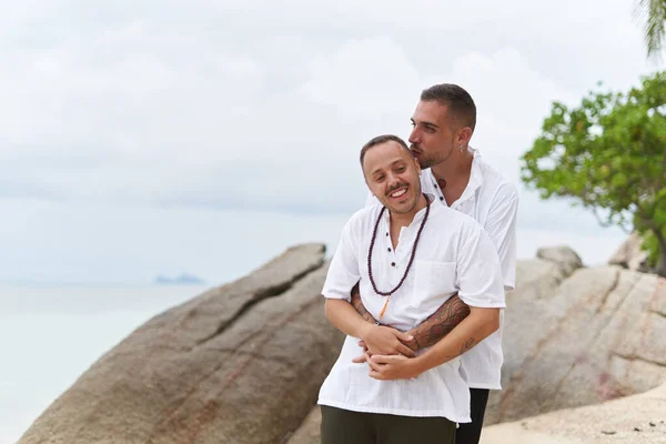 Feliz gay casal beijos e abraçando no um praia — Fotografia de Stock