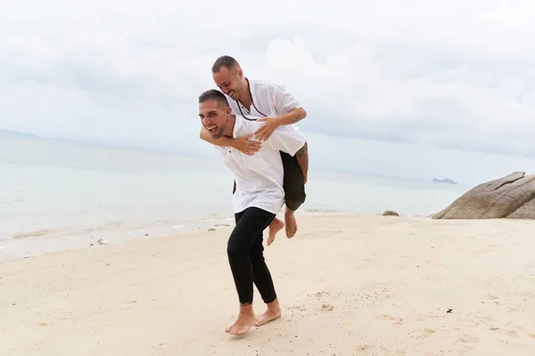 Man meeliften zijn gay partner op een strand — Stockfoto
