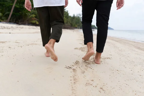 熱帯のビーチを歩く2人の男の裸足の足 — ストック写真