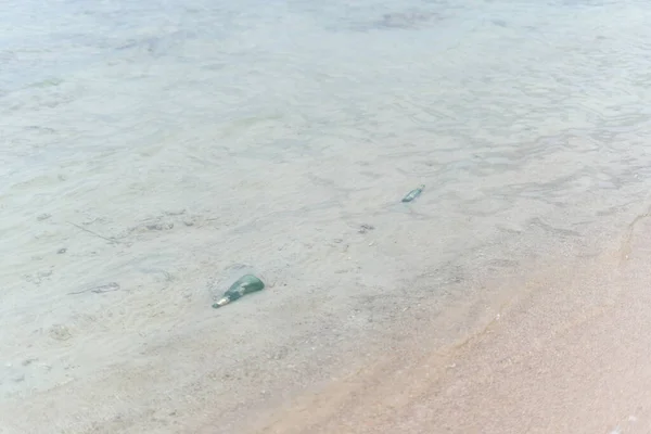 Botellas de vidrio amarradas en la arena del mar — Foto de Stock