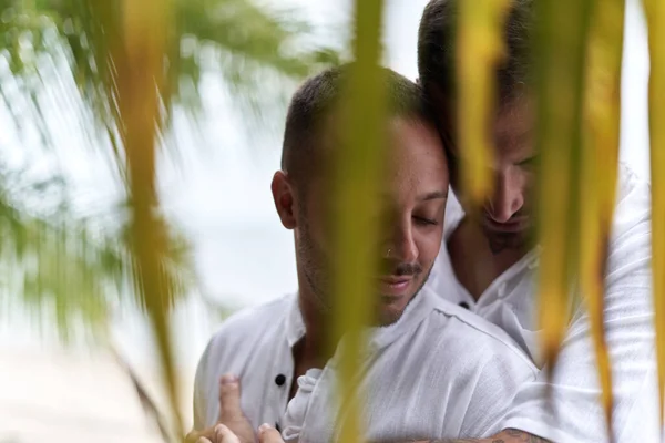 Coppia di gay che si coccola teneramente nelle foglie di un albero tropicale — Foto Stock