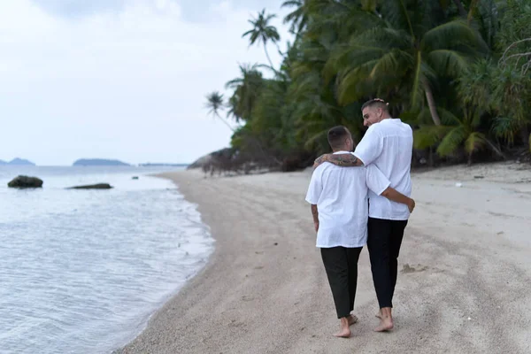 ゲイのカップルは夜にビーチに沿って歩く — ストック写真