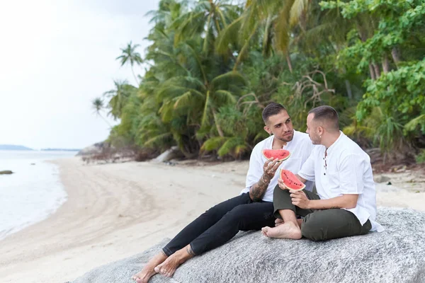 Foto mit Kopierraum eines homosexuellen Paares, das beim Essen einer Wassermelone plaudert — Stockfoto