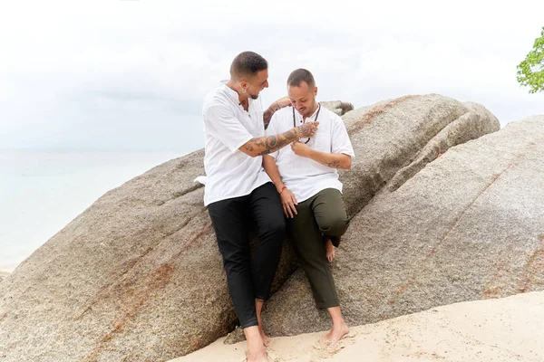 Homossexual homem colocando em um colar de bola para seu parceiro em uma praia tropical — Fotografia de Stock